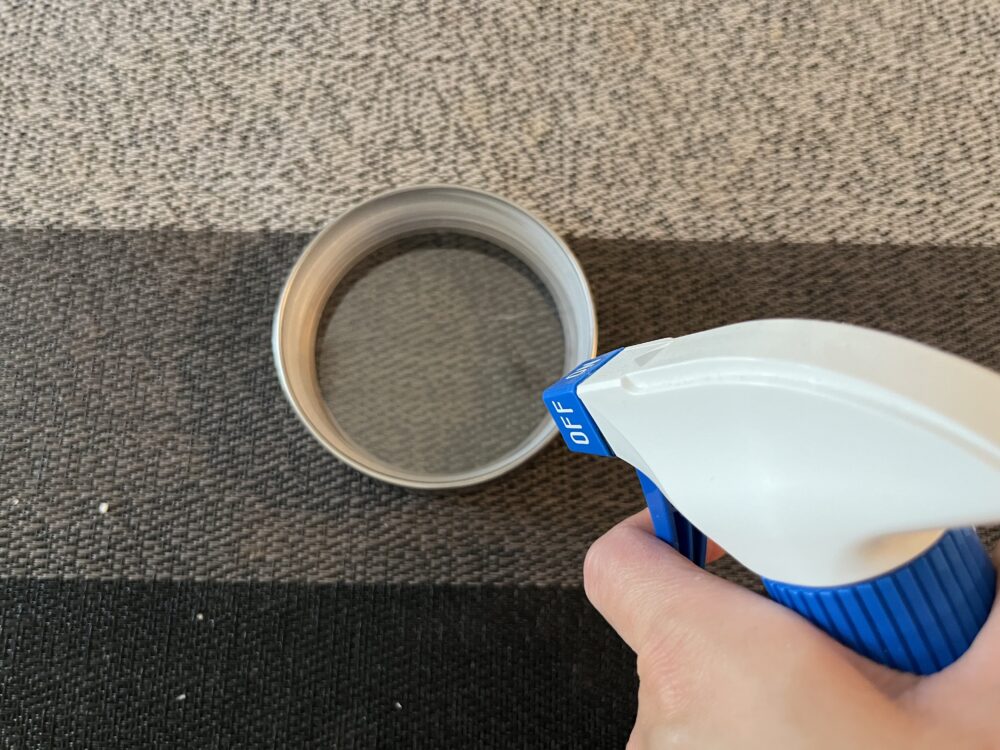 保存容器の蓋にアルコールスプレーをしている様子