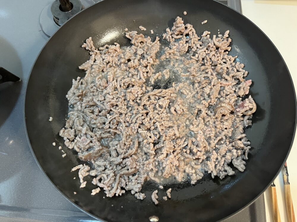 鉄フライパンで豚ひき肉を炒めている。